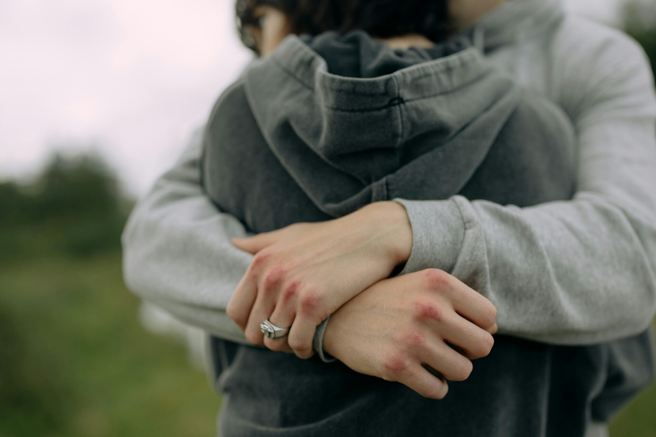 A close-up of two people embracing outdoors, showcasing warmth and affection.